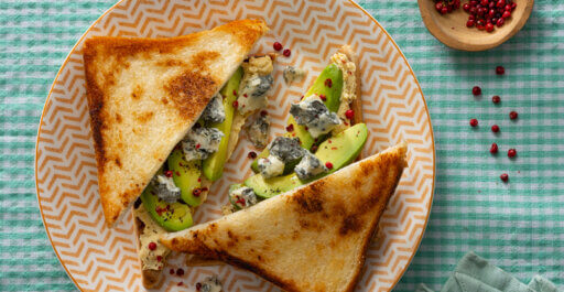 Toast met avocado, hummus, gorgonzola bob piccante en roze peper